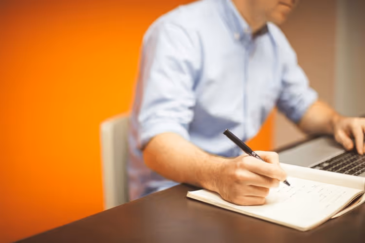 Freelancer pisze artykuł na laptopie z filiżanką kawy