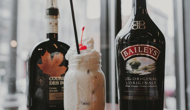 Creamy Baileys cocktail with cherry garnish, captured in a cozy indoor setting. Perfect for dessert drinks.