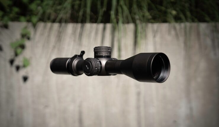 A close up of a rifle scope on a wooden surface